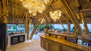 Zona de bar con temática de bambú, que incluye una barra, asientos e iluminación colgante.