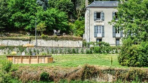 A two-story house with a stone wall and a garden in front. - Maison Volière (La Souterraine)