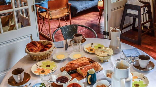 A dining area with a table set for breakfast, featuring bread, pastries, and various condiments. - Maison Volière (La Souterraine)