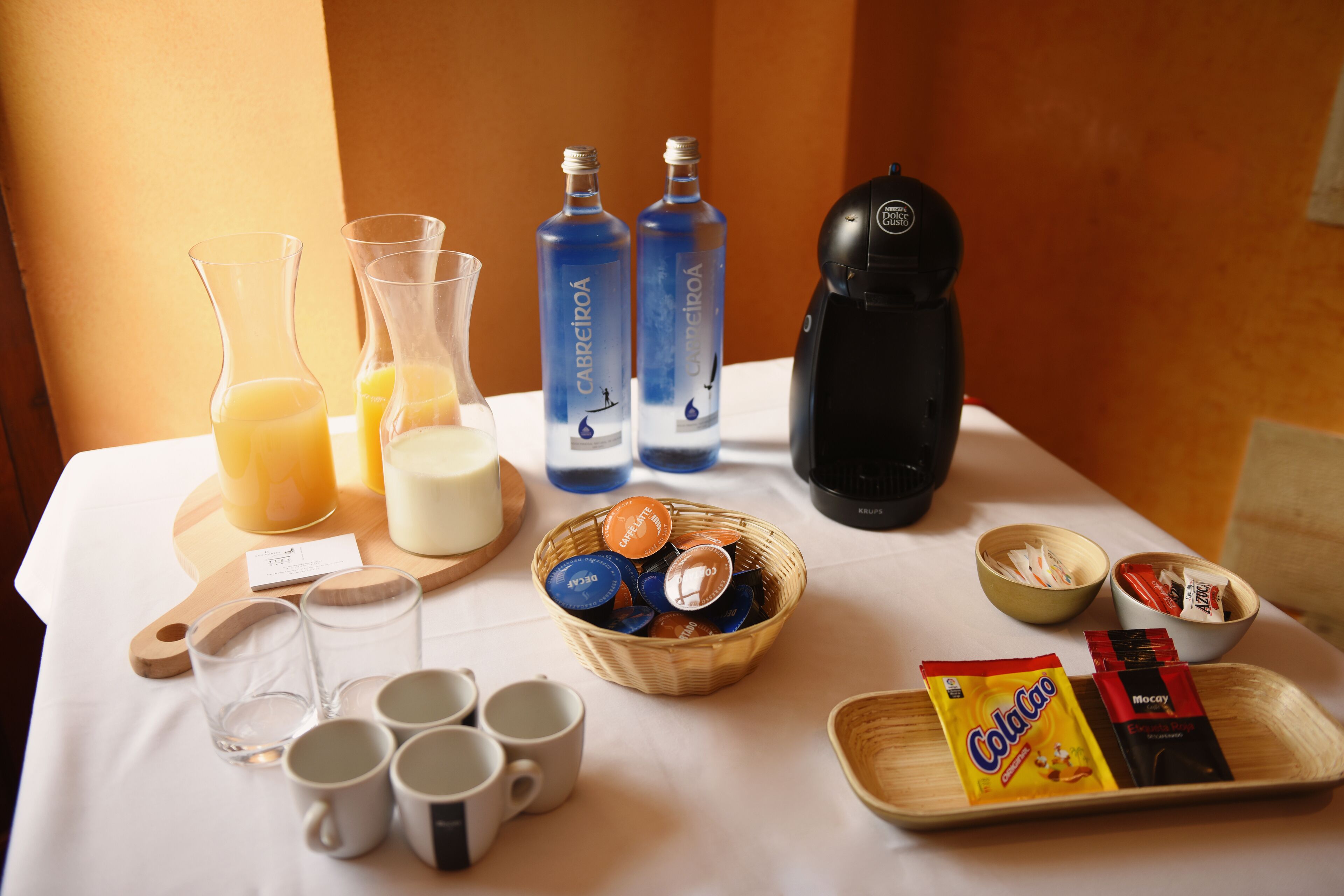 Una disposición para el desayuno con bebidas, tazas y aperitivos sobre una mesa.