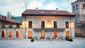 Un bâtiment en pierre dont la façade porte l’inscription « SAN MARTIN », avec de nombreuses fenêtres et une cour intérieure aménagée avec des sièges.