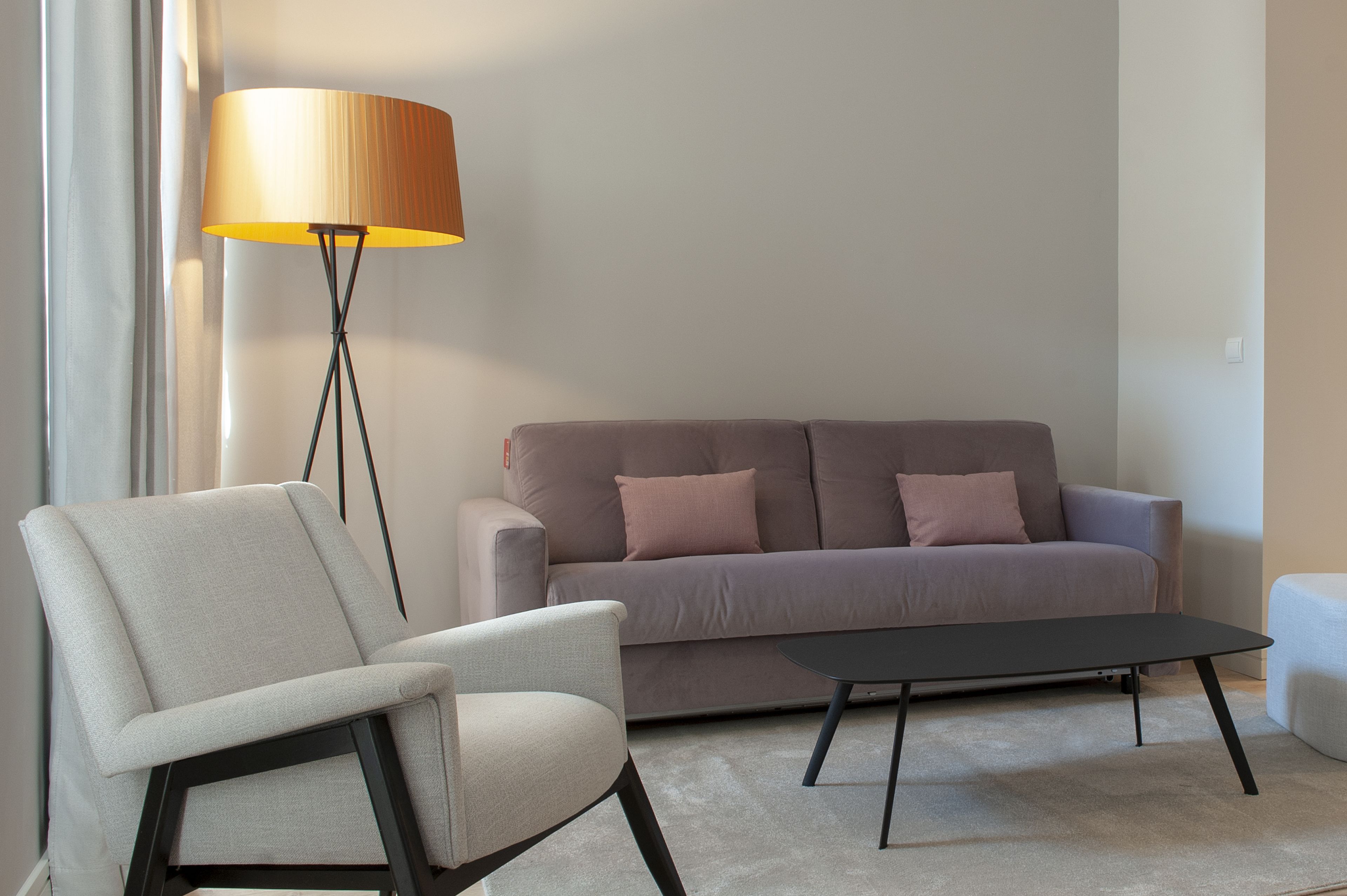 A modern living room with a sofa, a chair, a floor lamp, and a coffee table.