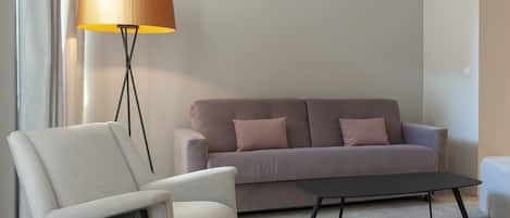 A modern living room with a sofa, a chair, a floor lamp, and a coffee table.