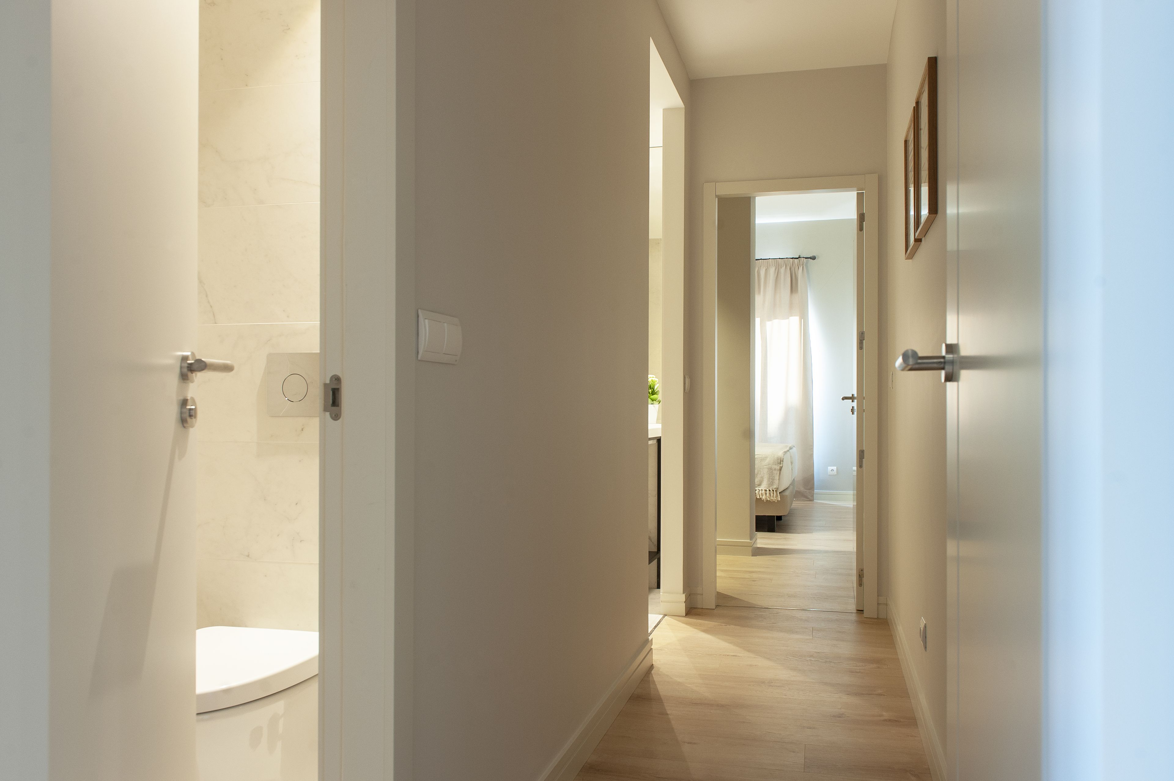 Un couloir avec des toilettes, un lit et une porte donnant sur une autre pièce.