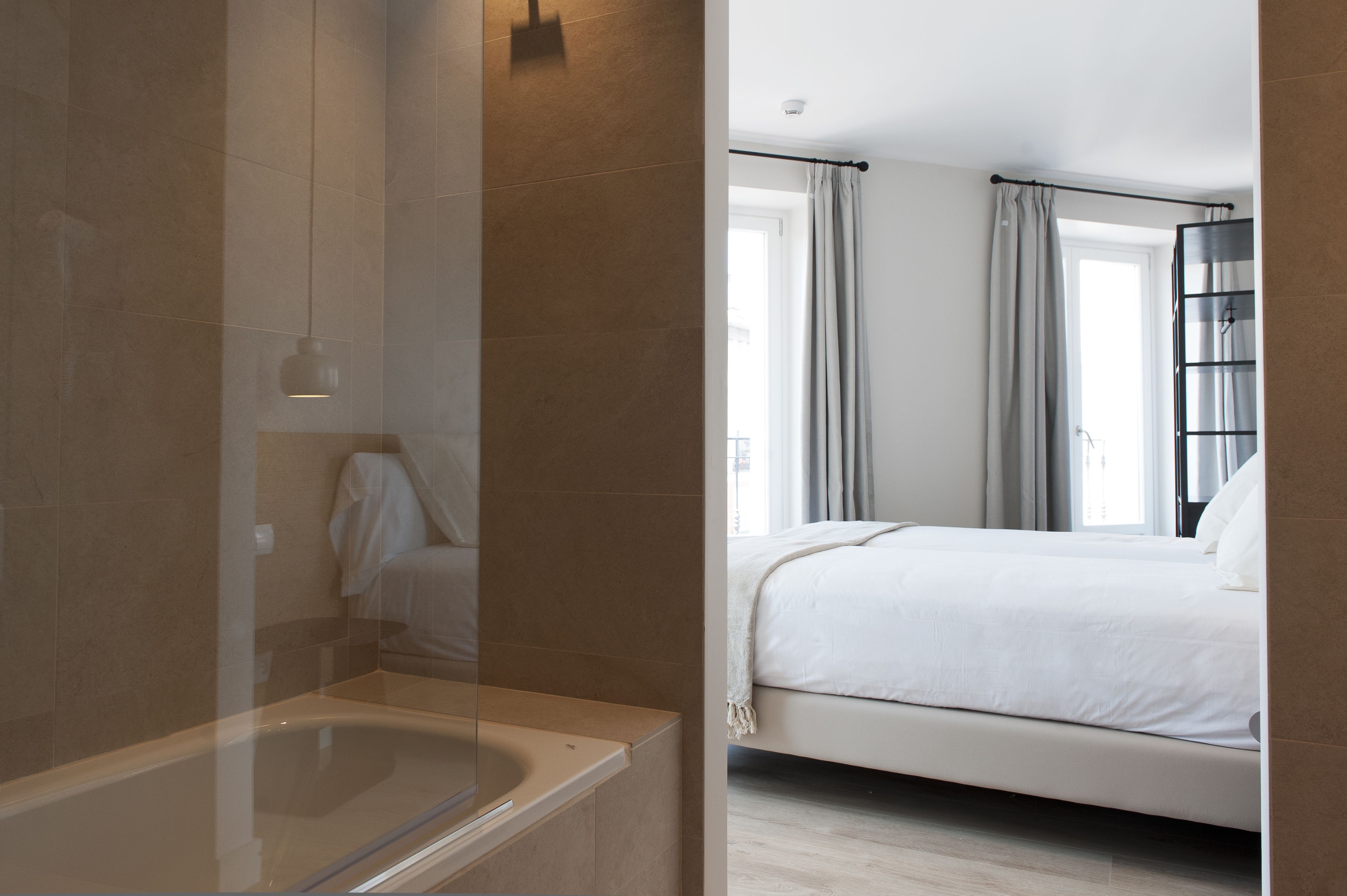 Ein modernes Badezimmer mit Badewanne, Duschbereich und großem Fenster mit Vorhängen.