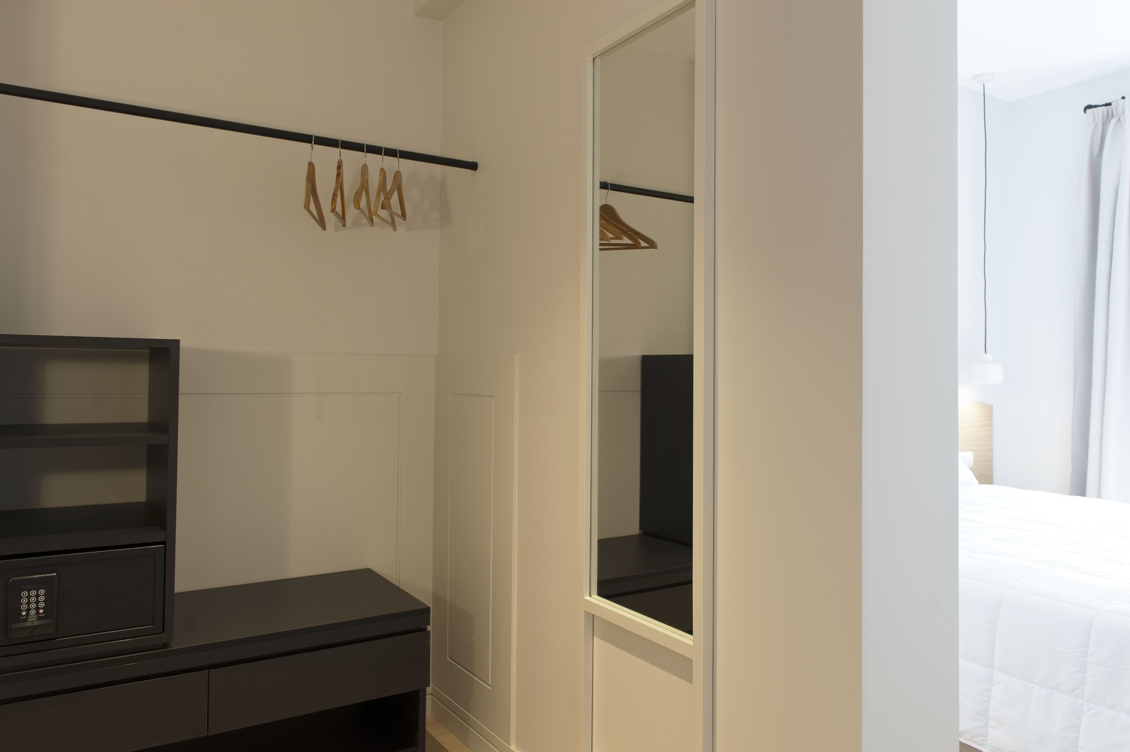 A hotel room with a black minibar, a mirror, and a hanging coat rack.