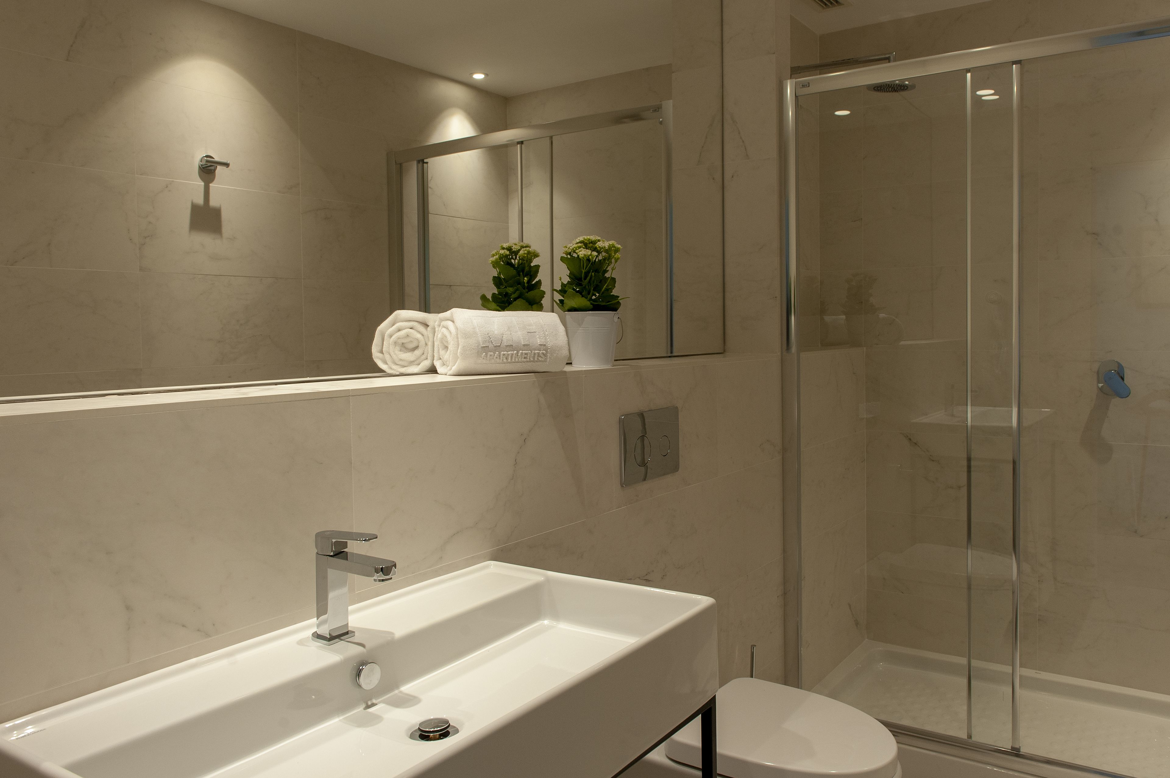 Une salle de bain moderne avec un grand lavabo, des toilettes et une douche à parois de verre.