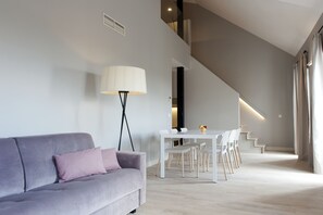 A modern living room with a sofa, a lamp, and a dining area with chairs and a table. - MH Apartments Central Madrid (Madrid)