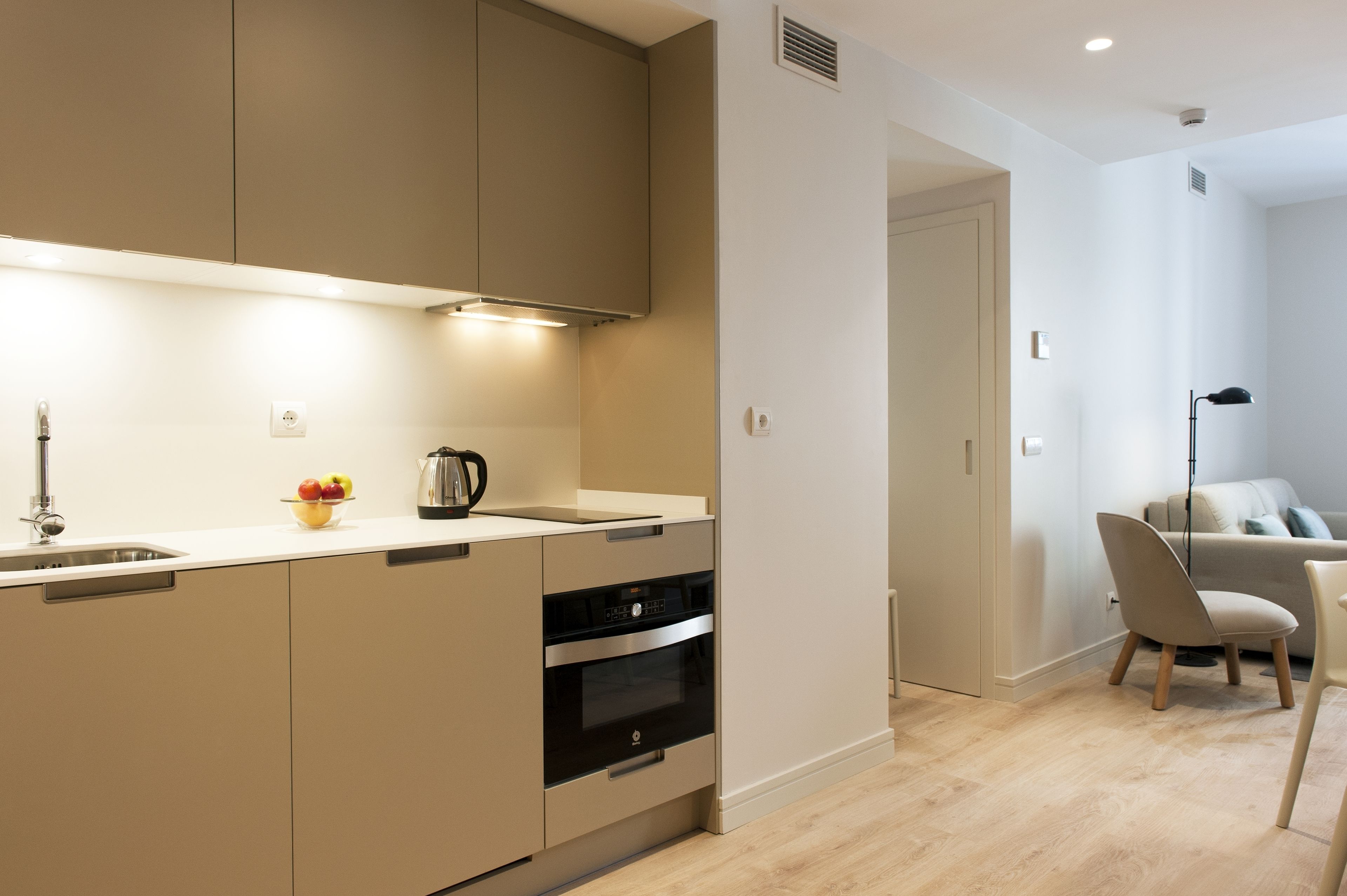 A modern kitchen with a built-in oven, a coffee maker, and a fruit bowl on the counter.