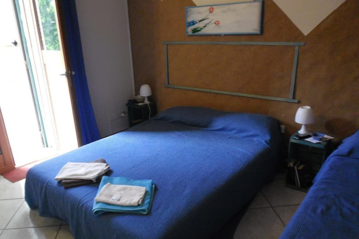 A hotel room with a bed, a nightstand, a lamp, and a painting on the wall.