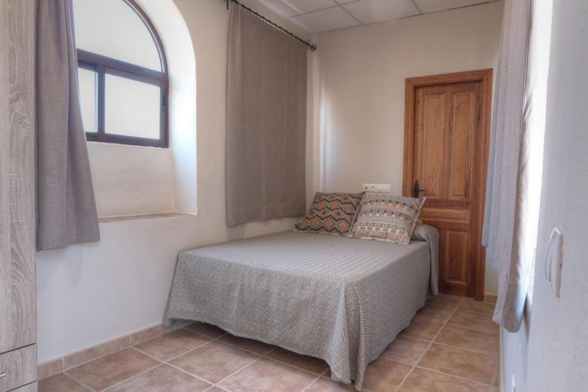 A small bedroom with a bed, a window, and a door.