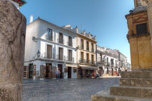 Una calle adoquinada con edificios históricos, balcones y una fuente.