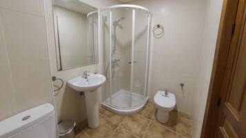Een badkamer met douche, wastafel, toilet en spiegel.