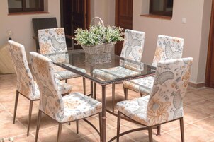 Un comedor con una mesa de vidrio rodeada de sillas con estampado floral.