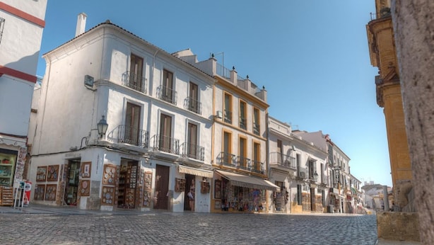 Una calle adoquinada con edificios tradicionales, escaparates y balcones.
