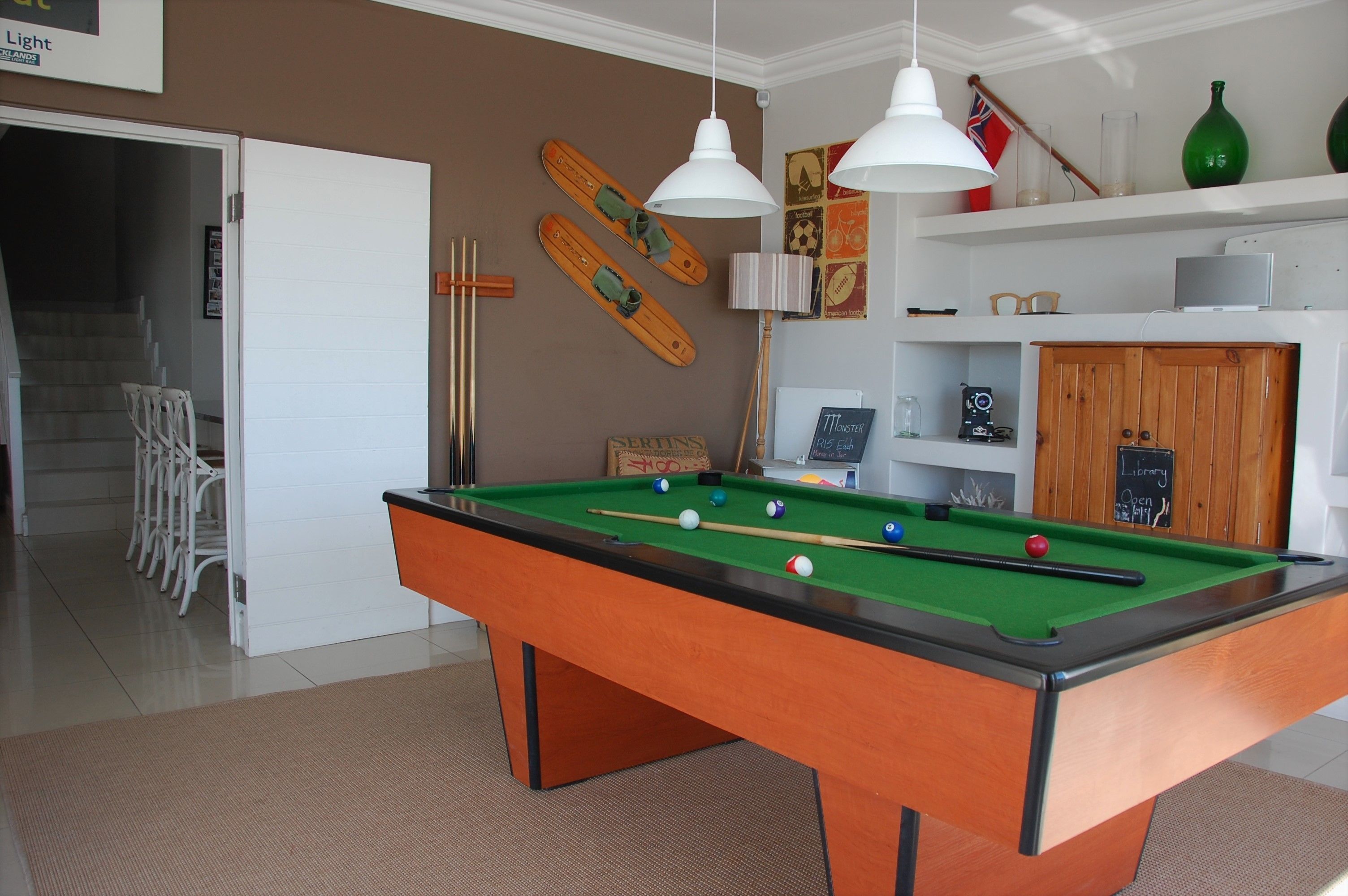 Une table de billard avec des billes, une porte blanche et un escalier.