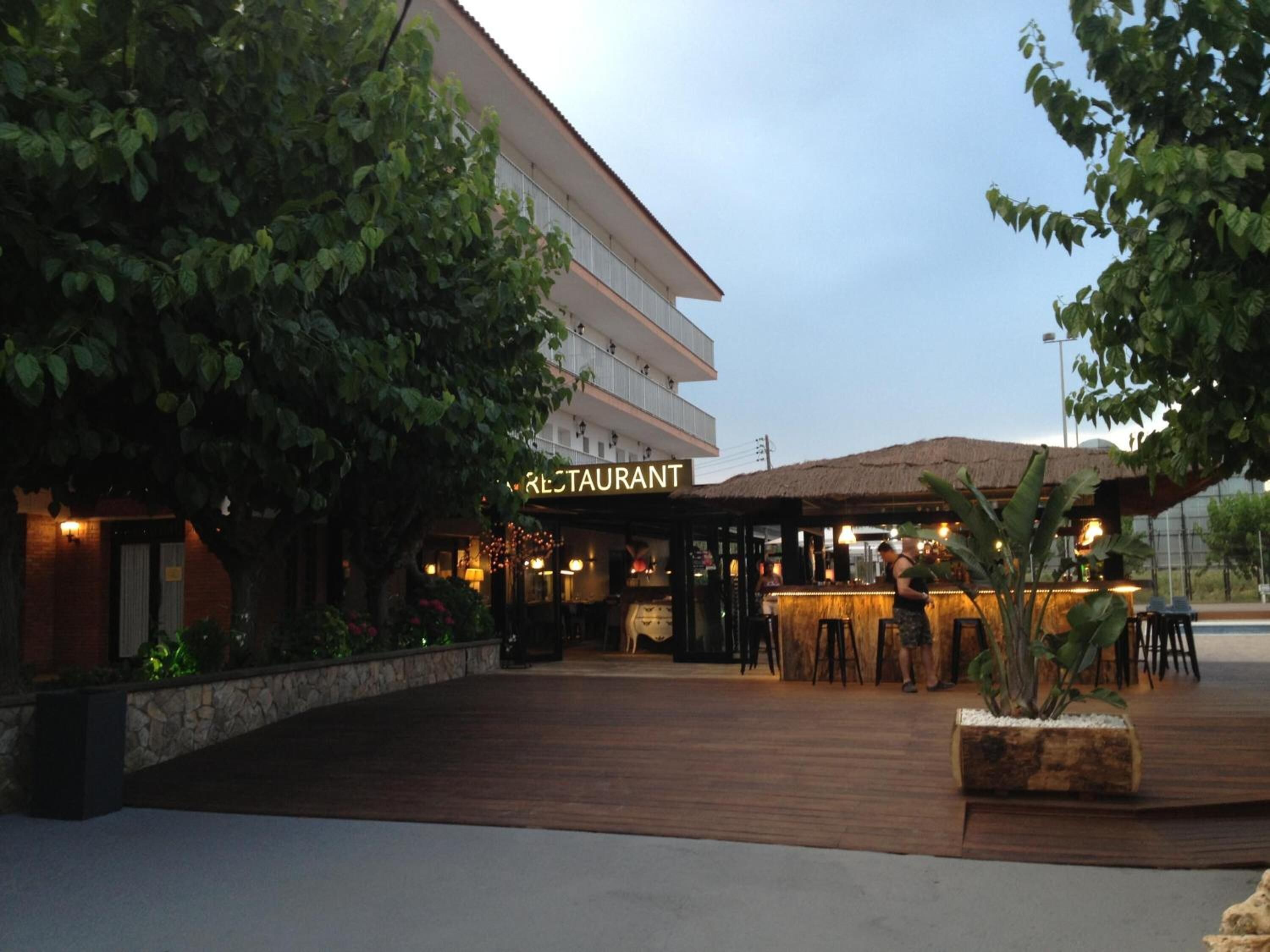 A restaurant with outdoor seating, a stone wall, and a building with a sign.