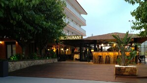 A restaurant with outdoor seating, a bar area, and a covered patio. - Hostal Solfina (Palafolls)