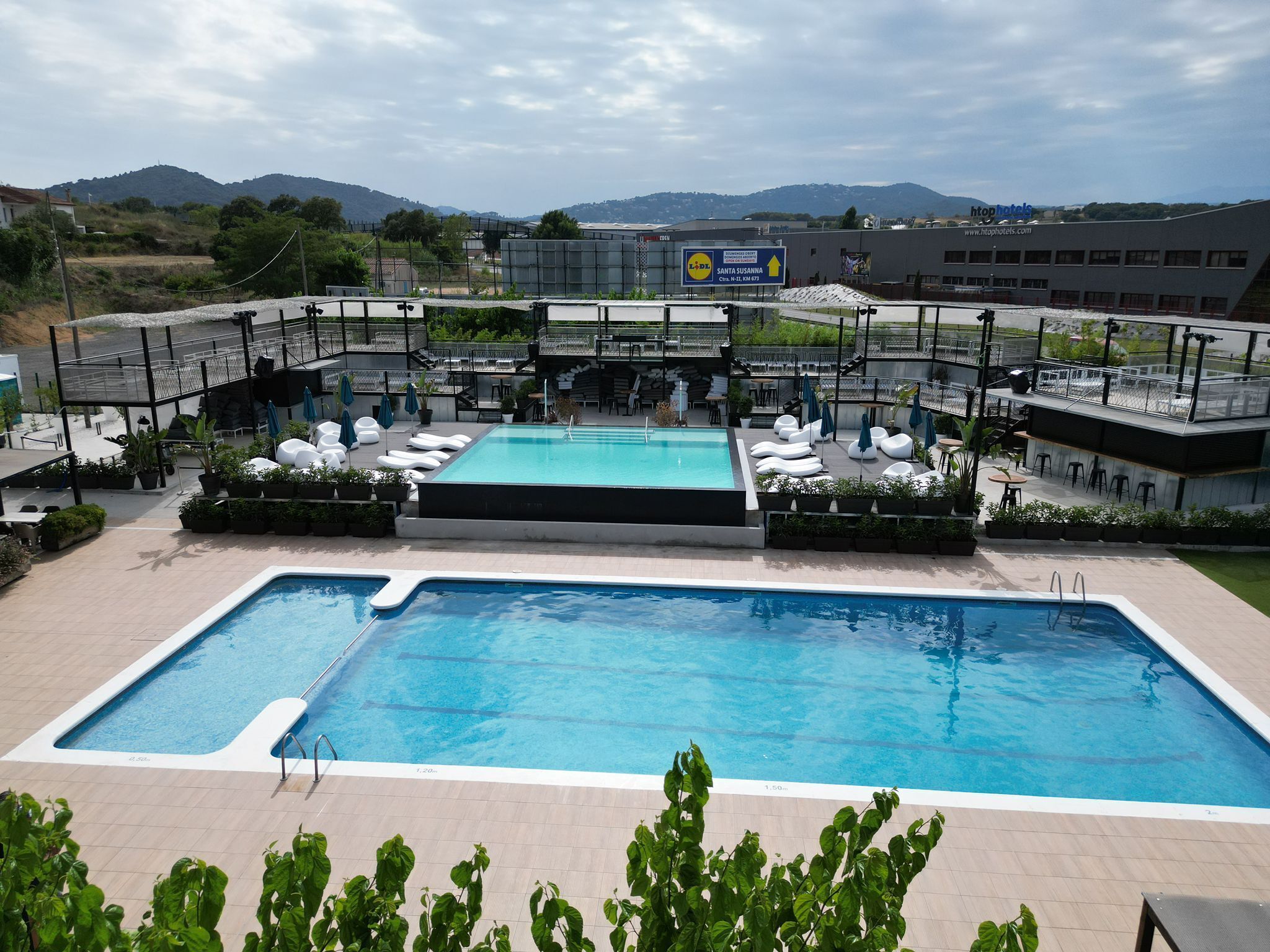 Un área de piscina en la azotea con sillones reclinables y vistas al paisaje circundante.