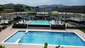 Un área de piscina en la azotea con sillones reclinables y vistas al paisaje circundante.