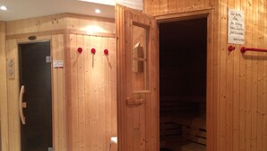 Ein Holz-Saunaraum mit Tür, Handtuchhalter und einem Schild an der Wand.