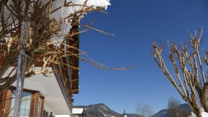 Ein mit Schnee bedecktes Gebäude mit einer Holzfassade und blauem Himmel.