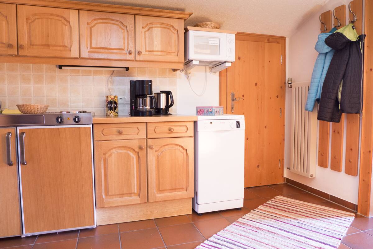 A kitchen with wooden cabinets, a coffee maker, a microwave, and a dishwasher.