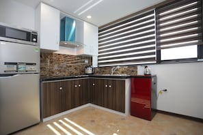 A kitchen with a microwave, refrigerator, and red mini-fridge.