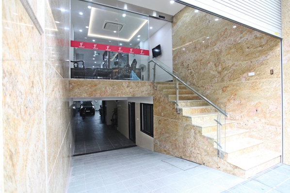 A modern interior with a marble staircase, a glass railing, and a ceiling with recessed lighting.