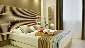 Una habitación de hotel moderna con una cama grande, cabecera de madera, mesitas de noche y una bandeja con artículos para el desayuno.
