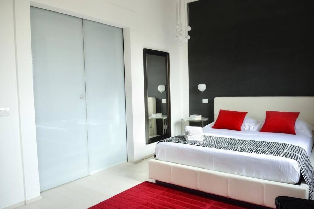 Ein modernes Schlafzimmer mit einem großen Bett, einem roten Teppich und einer Schiebetür.