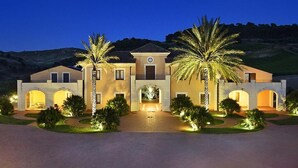 A large, well-lit building with multiple arches and palm trees in front. - Baglio Caruana Cantina & Relais (Siculiana)