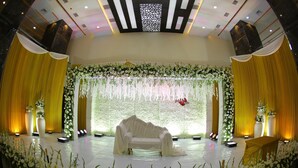 A stage with a white sofa, yellow drapes, and floral decorations. - Hotel Lance International (Nagercoil)