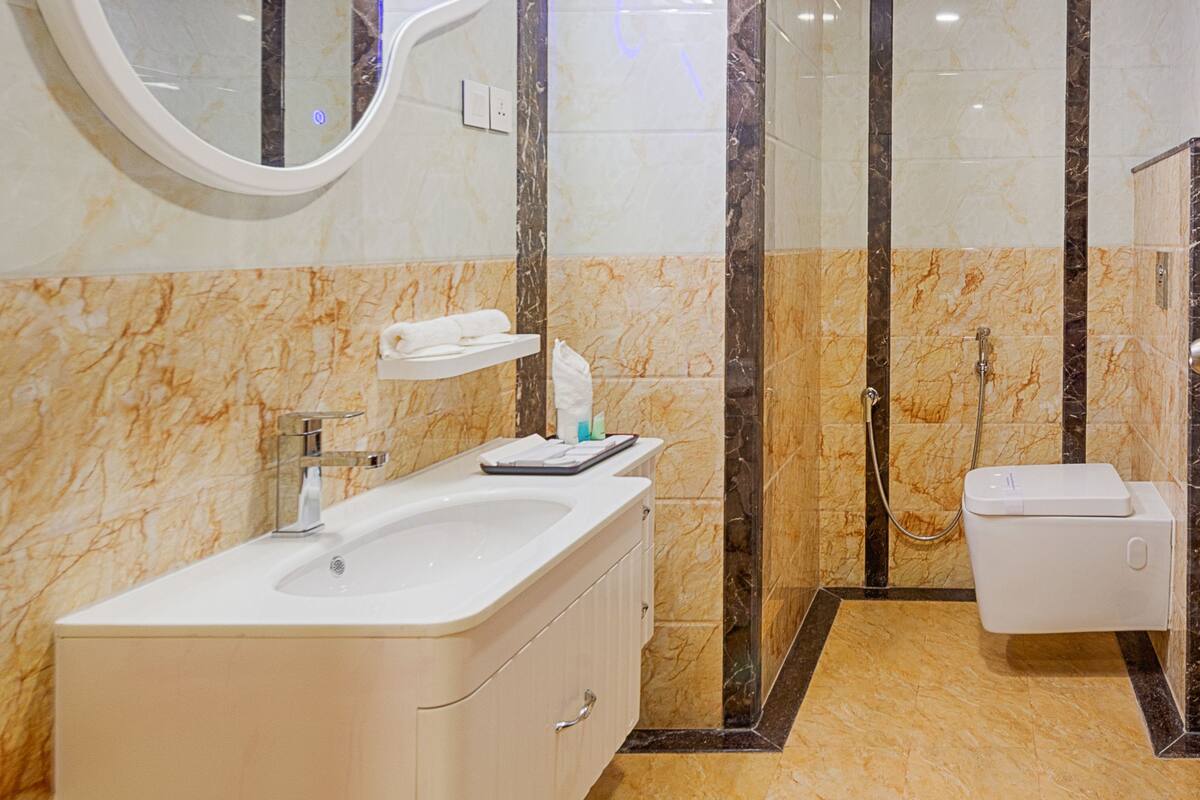 A modern bathroom with a large mirror, a sink, and a shower area.