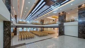 A spacious hall with tiered seating and a modern ceiling design. - Hotel Lance International (Nagercoil)
