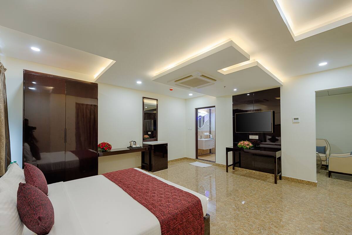 A hotel room with a bed, a desk, a TV, a mirror, and a bathroom.