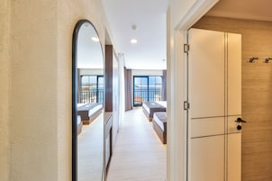 A corridor leading to a bedroom with a balcony, a large mirror, and a wardrobe.