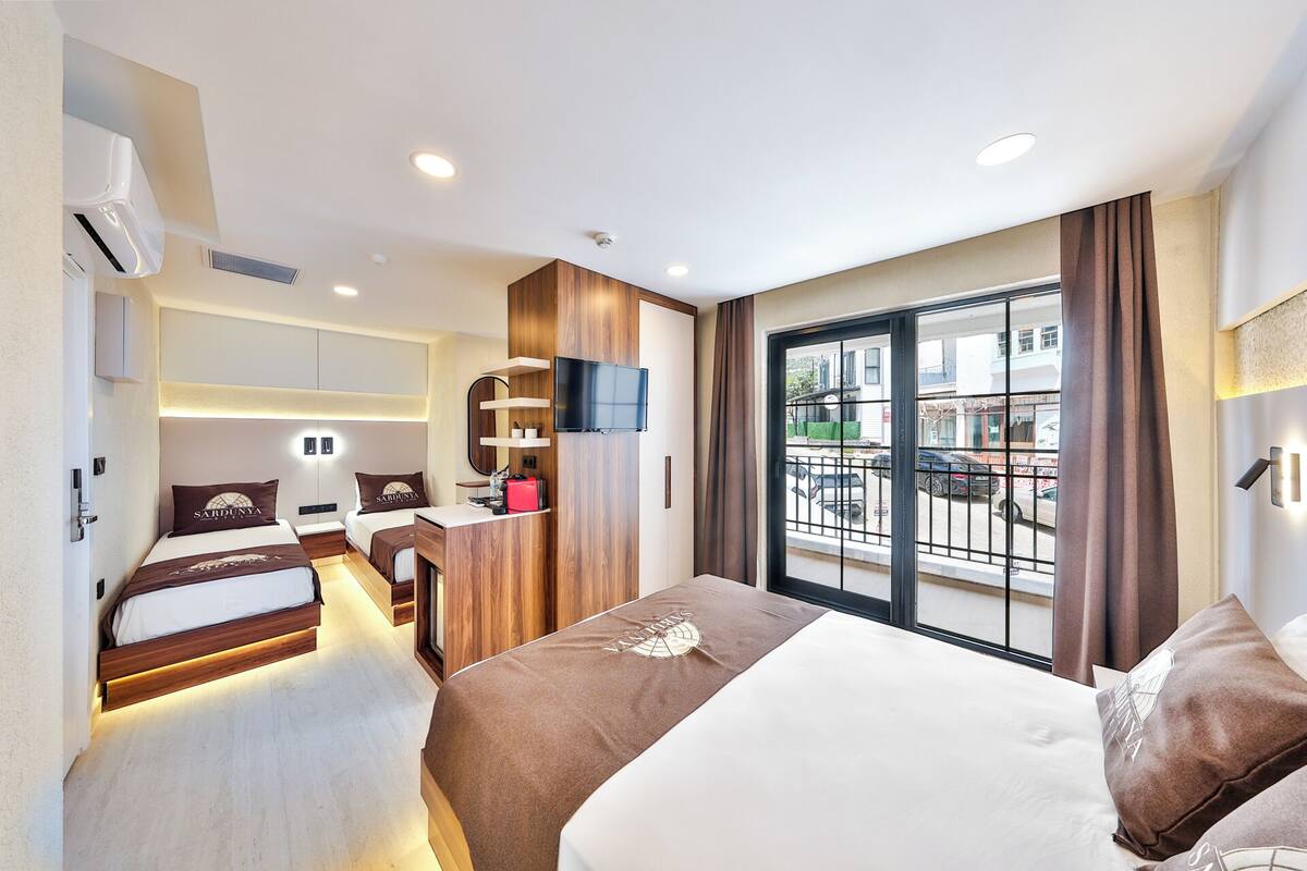 A hotel room with a bed, bedside tables, a TV, a small desk, and a balcony with a view.