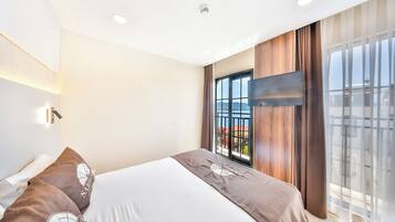 Een moderne hotelkamer met een groot bed, een aan de muur bevestigde televisie en een balkon met uitzicht.