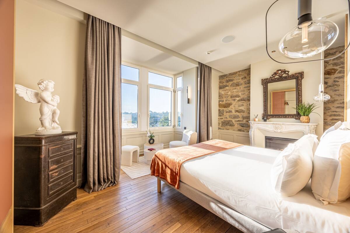 A bedroom with a large bed, a dresser, a mirror, and a statue of an angel.