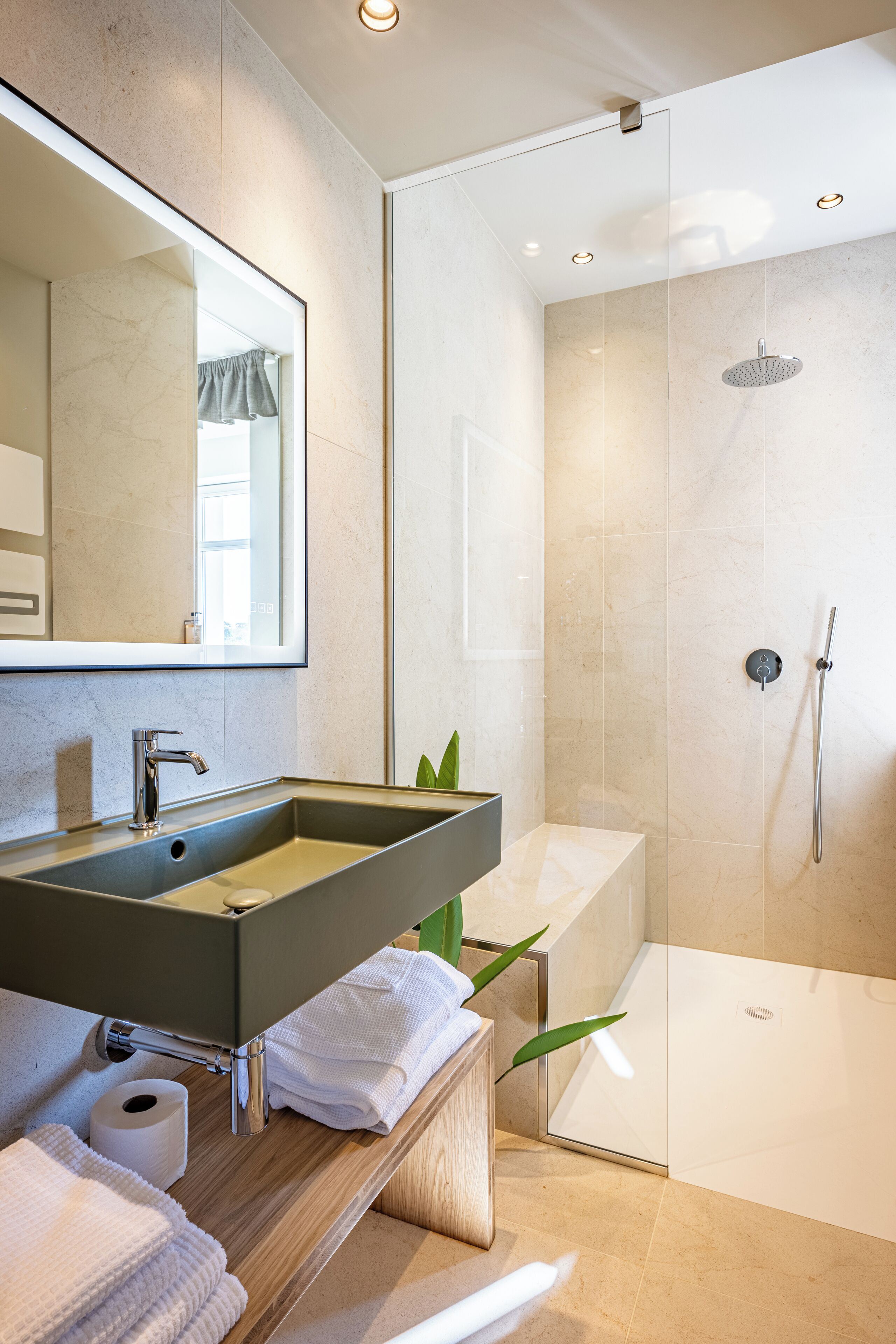 A modern bathroom with a large mirror, a sink, a shower, and a toilet.