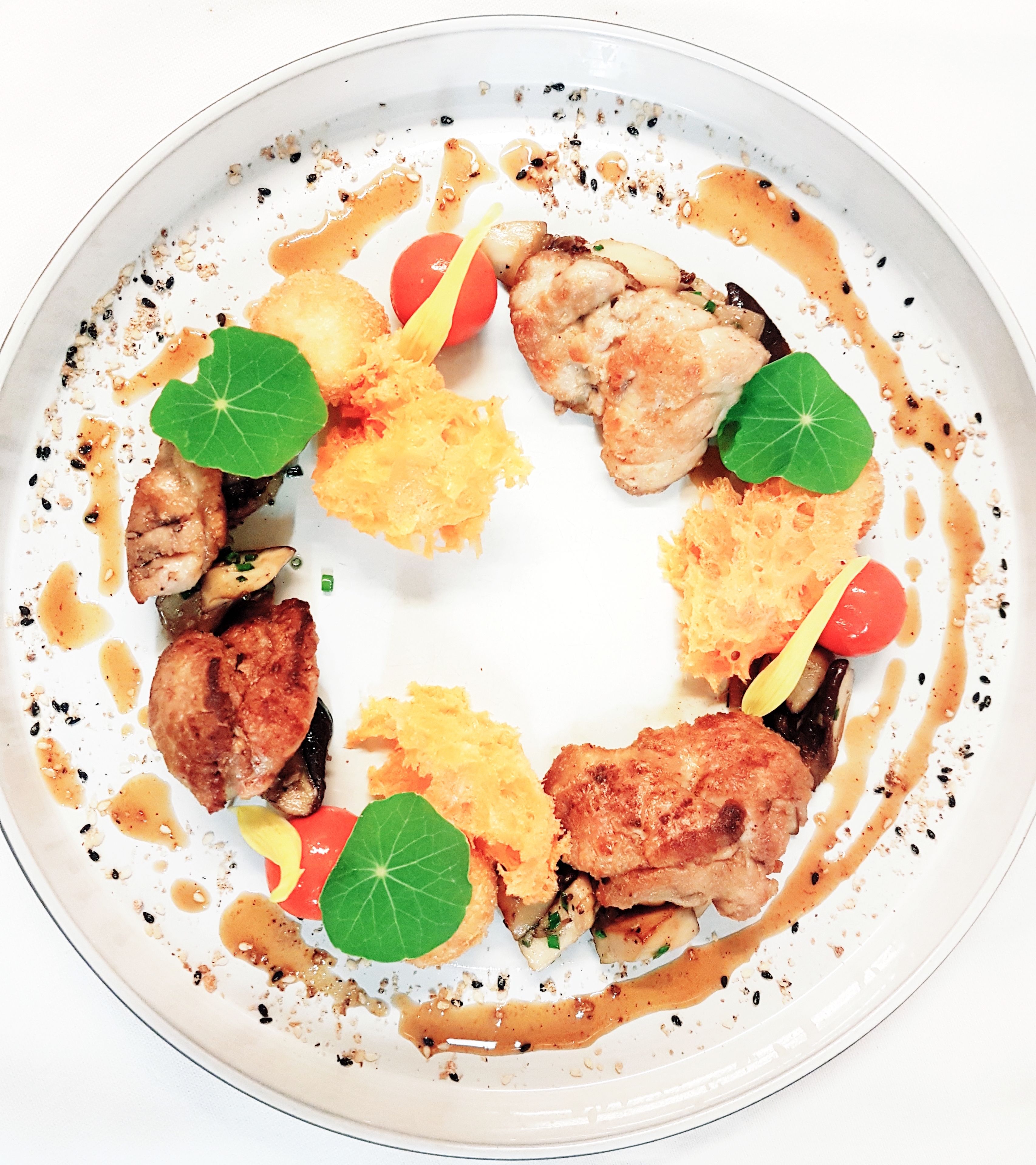 Un plato blanco con una variedad de alimentos, incluyendo lo que parece ser pollo, verduras y guarniciones.
