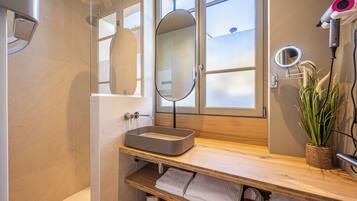 Une salle de bain moderne avec une douche à parois de verre, un meuble-lavabo en bois et un sèche-cheveux fixé au mur.