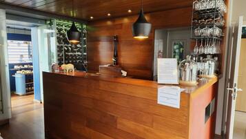 A wooden reception desk with hanging wine glasses and a menu sign.