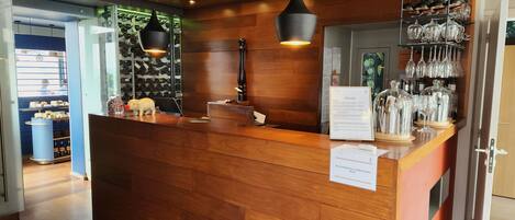 A wooden reception desk with hanging wine glasses and a menu sign.