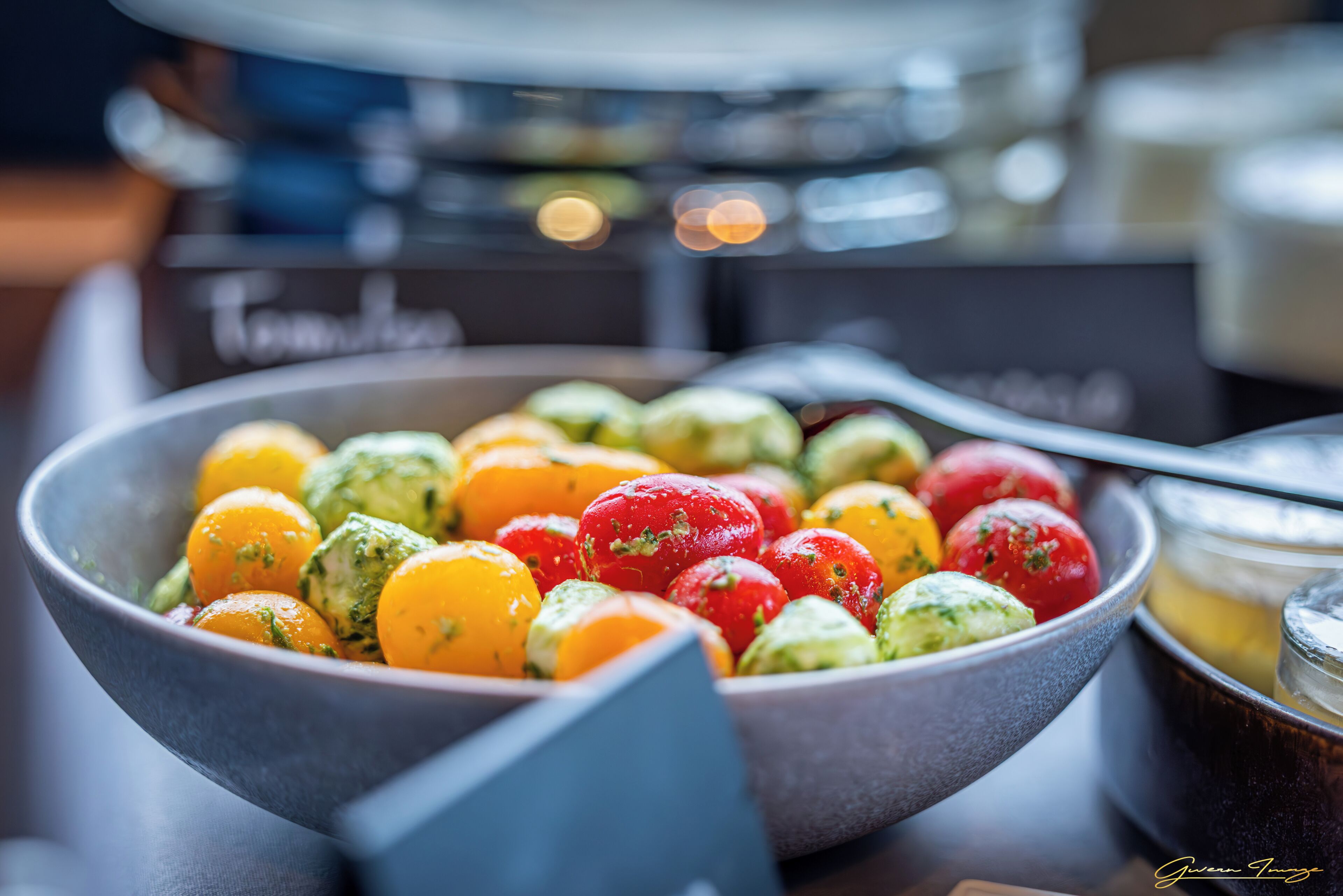 A bowl of assorted fruits including oranges, tomatoes, and avocados.