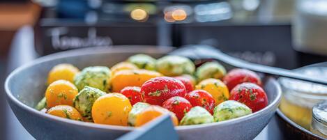A bowl of assorted fruits including oranges, tomatoes, and avocados.