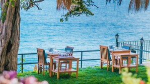 A seaside dining area with wooden tables and chairs, overlooking the sea. - Sardunya Andifli Otel (Kas)