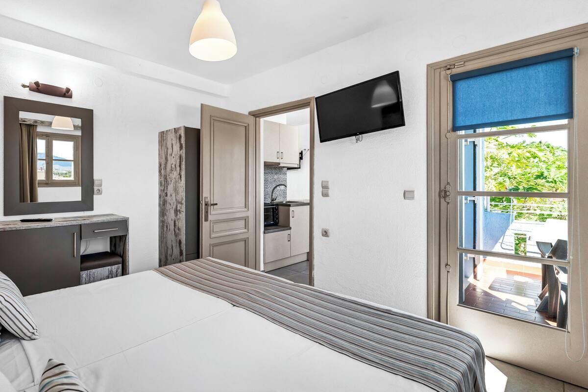 A bedroom with a bed, bedside table, lamp, and a TV mounted on the wall.