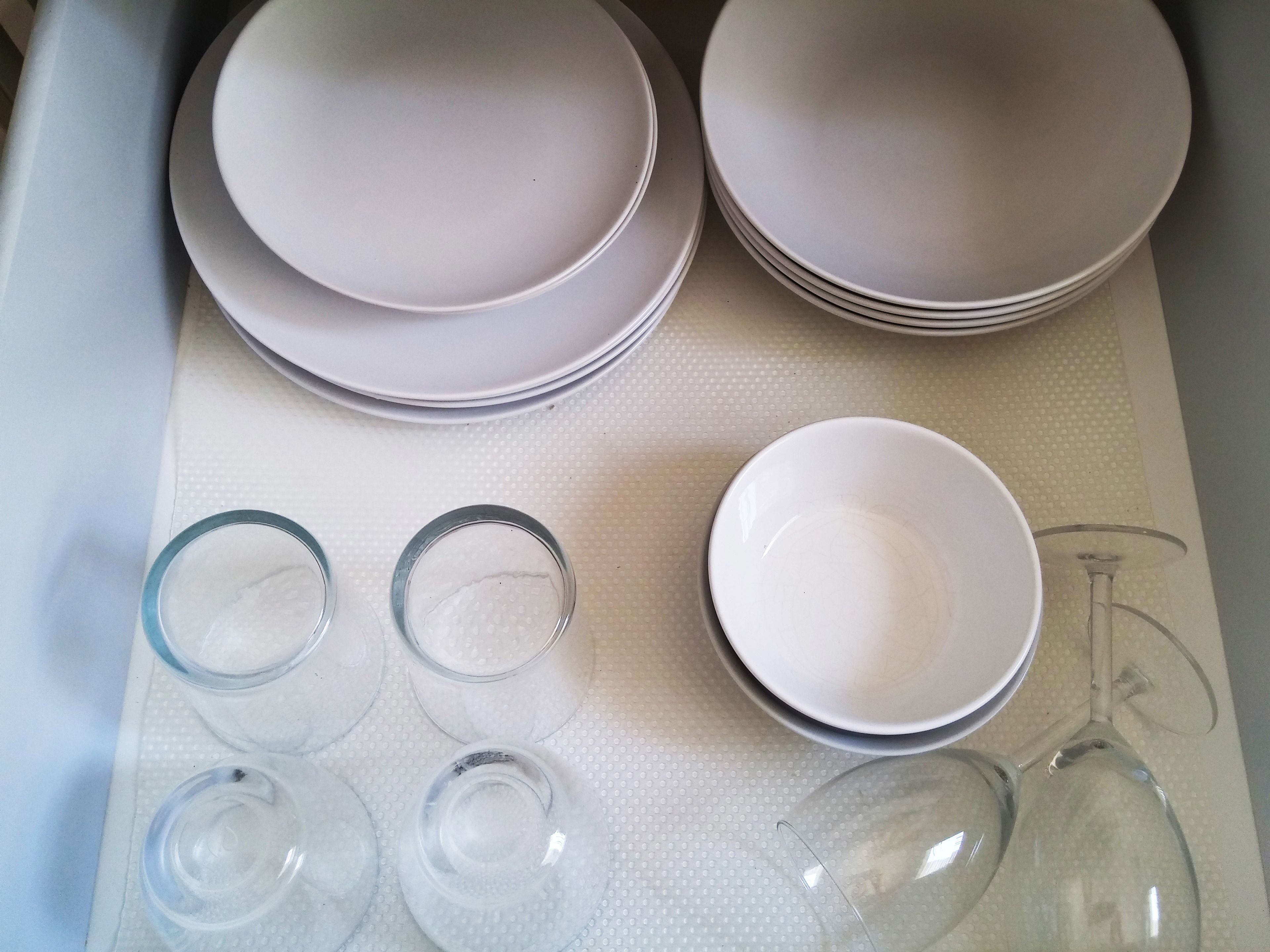 Un plateau avec des assiettes empilées et des verres transparents.